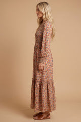 woman wearing a long floral maxi dress with long sleeves and a tiered hem, styled with brown sandals