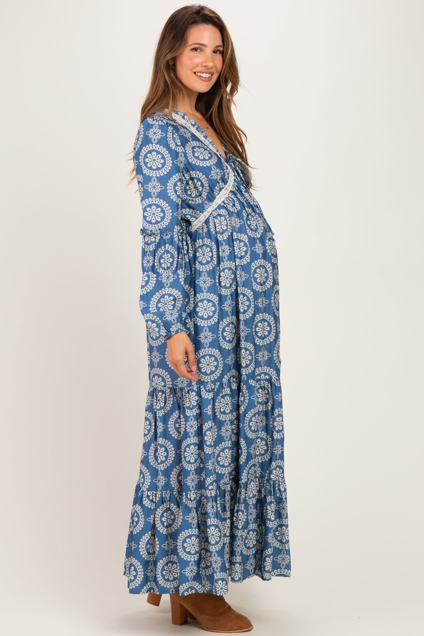 woman wearing a blue patterned long sleeve maternity dress with a flowing skirt and visible baby bump