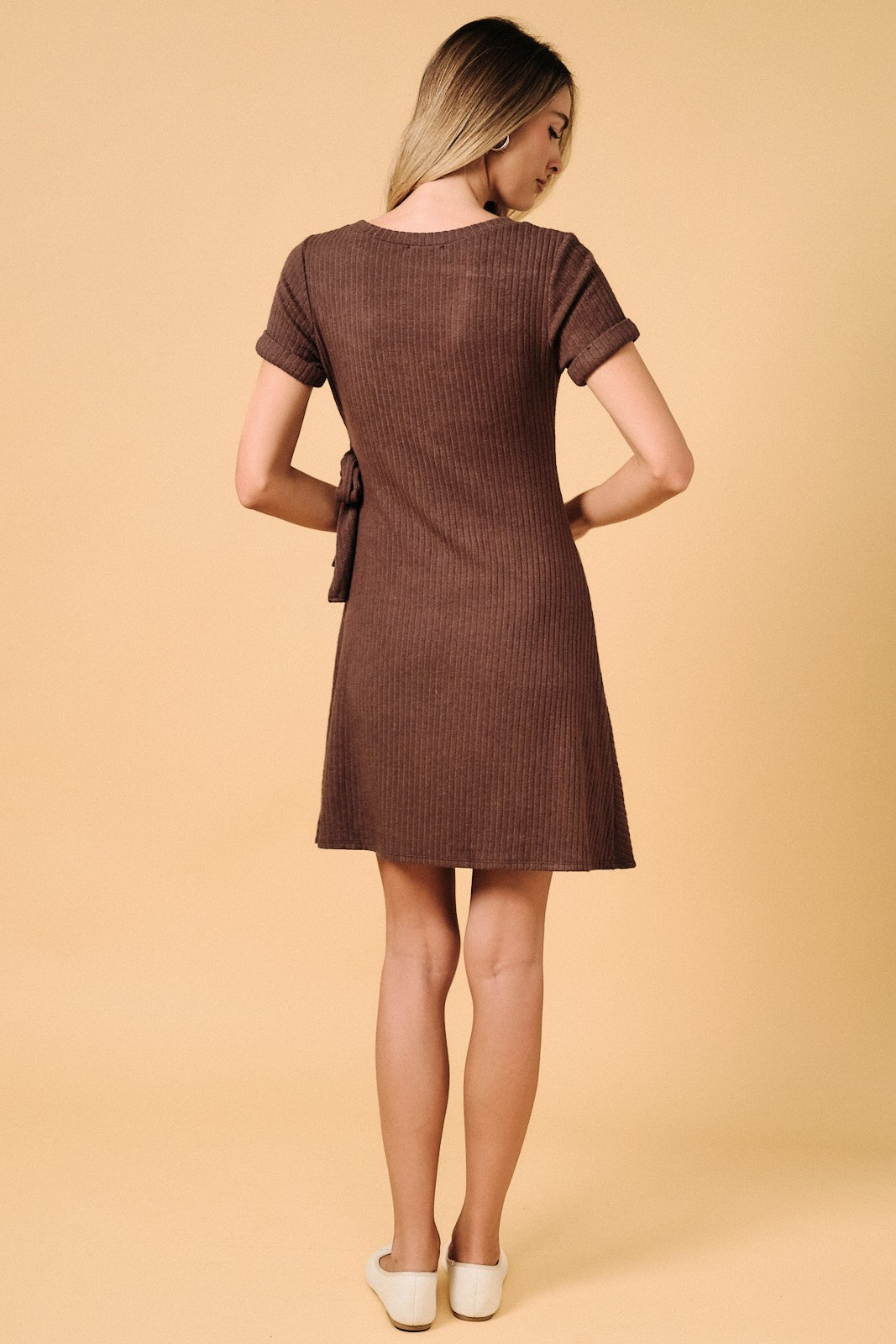 woman wearing a brown ribbed short sleeve dress with a tie detail at the back