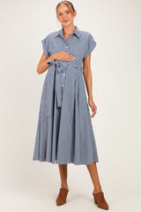 woman wearing a navy and white checkered maternity dress with short sleeves and a tie waist, holding her baby bump