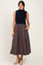 woman wearing a navy sleeveless top and a striped midi skirt with pockets, standing and smiling