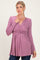 woman wearing a mauve long sleeve wrap top with a gathered waist and flowy hem, styled with dark jeans
