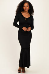 woman wearing a black ribbed maxi dress with a tie front and flared hem