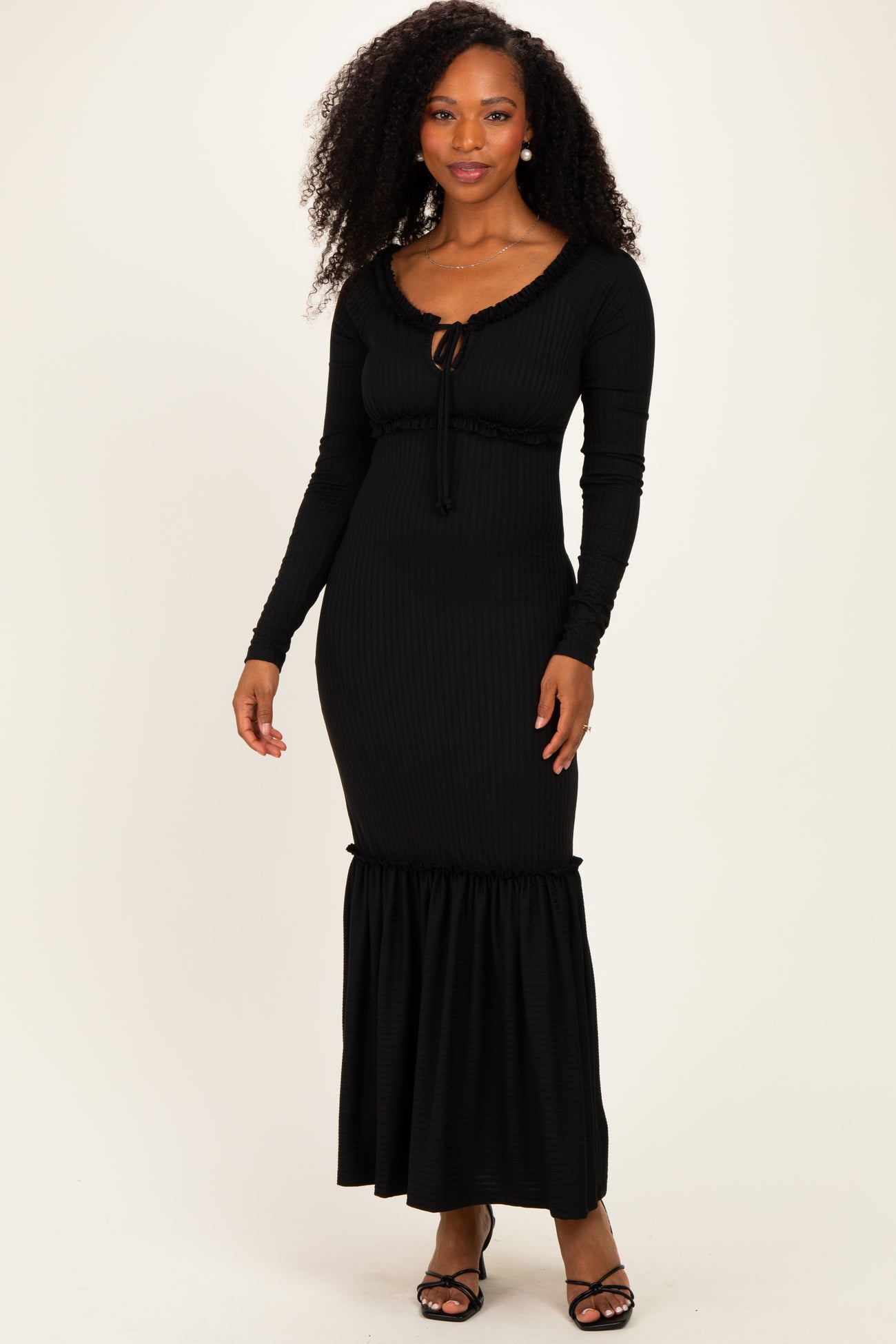 woman wearing a black ribbed maxi dress with long sleeves and ruffle hemline