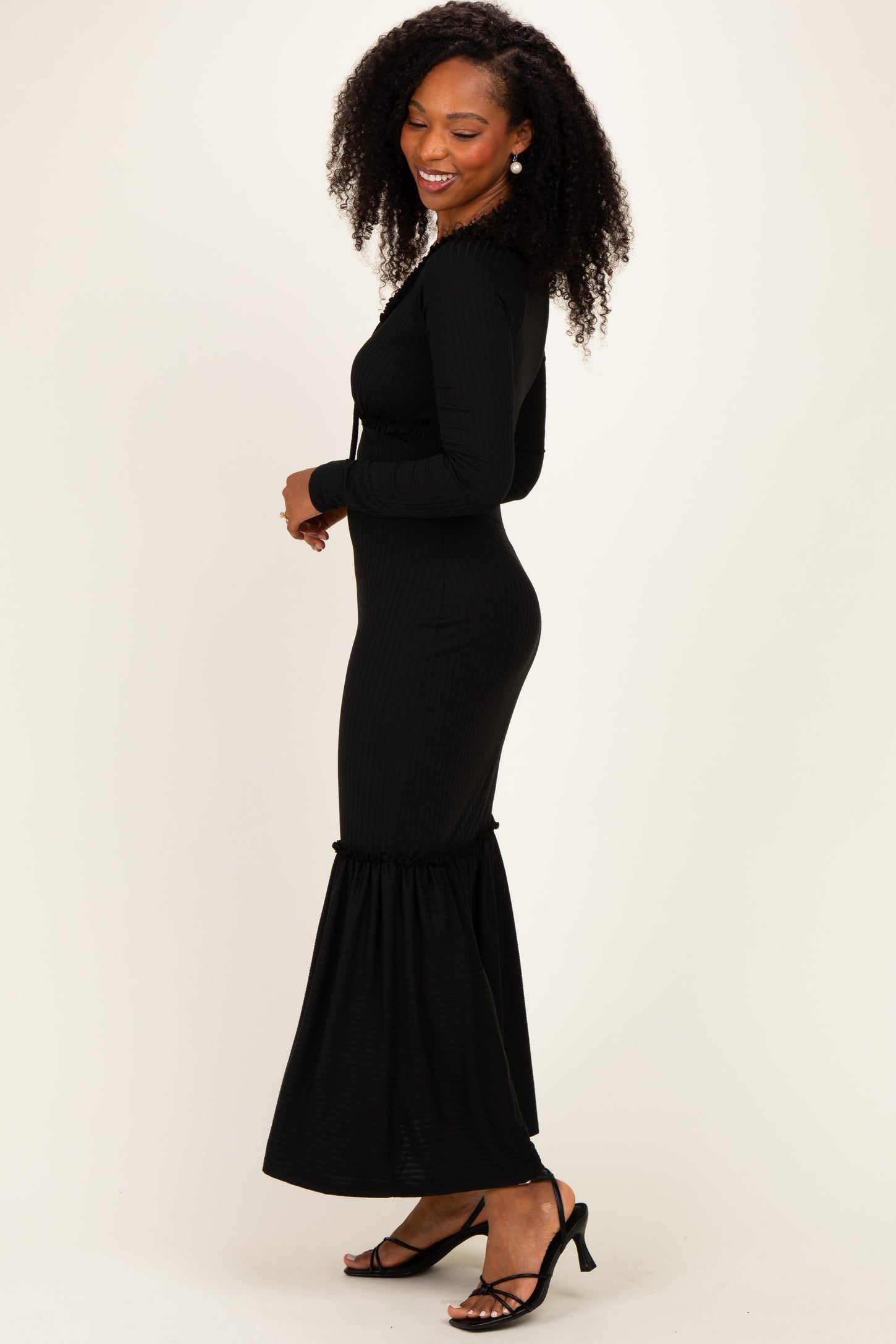 woman wearing a black ribbed long sleeve maxi dress with a flared hem and side drawstring detail