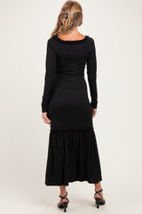 woman wearing a black ribbed maternity maxi dress with long sleeves and a ruffled hem, showing her back