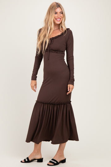 woman wearing a brown ribbed long sleeve maxi dress with a ruffled hem and a tie detail at the neckline