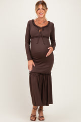woman wearing a brown long sleeve maternity maxi dress with ruffle details and a baby bump visible