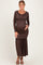woman wearing a brown long sleeve maternity maxi dress with ruffle details and a baby bump visible