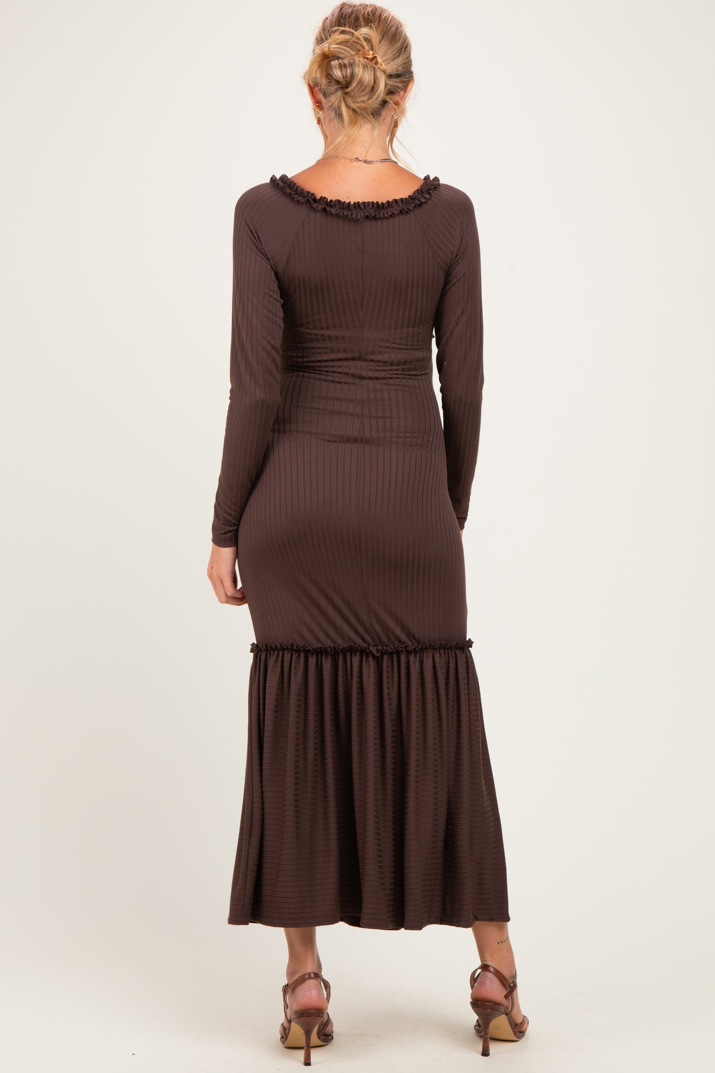 woman wearing a brown ribbed maternity dress with a flared hem and long sleeves, showing a baby bump