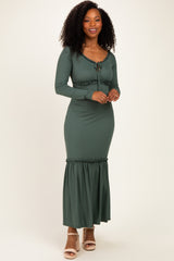 woman wearing a dark green ribbed maxi dress with long sleeves and a drawstring detail at the waist