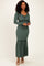woman wearing a dark green ribbed maxi dress with long sleeves and a drawstring detail at the waist