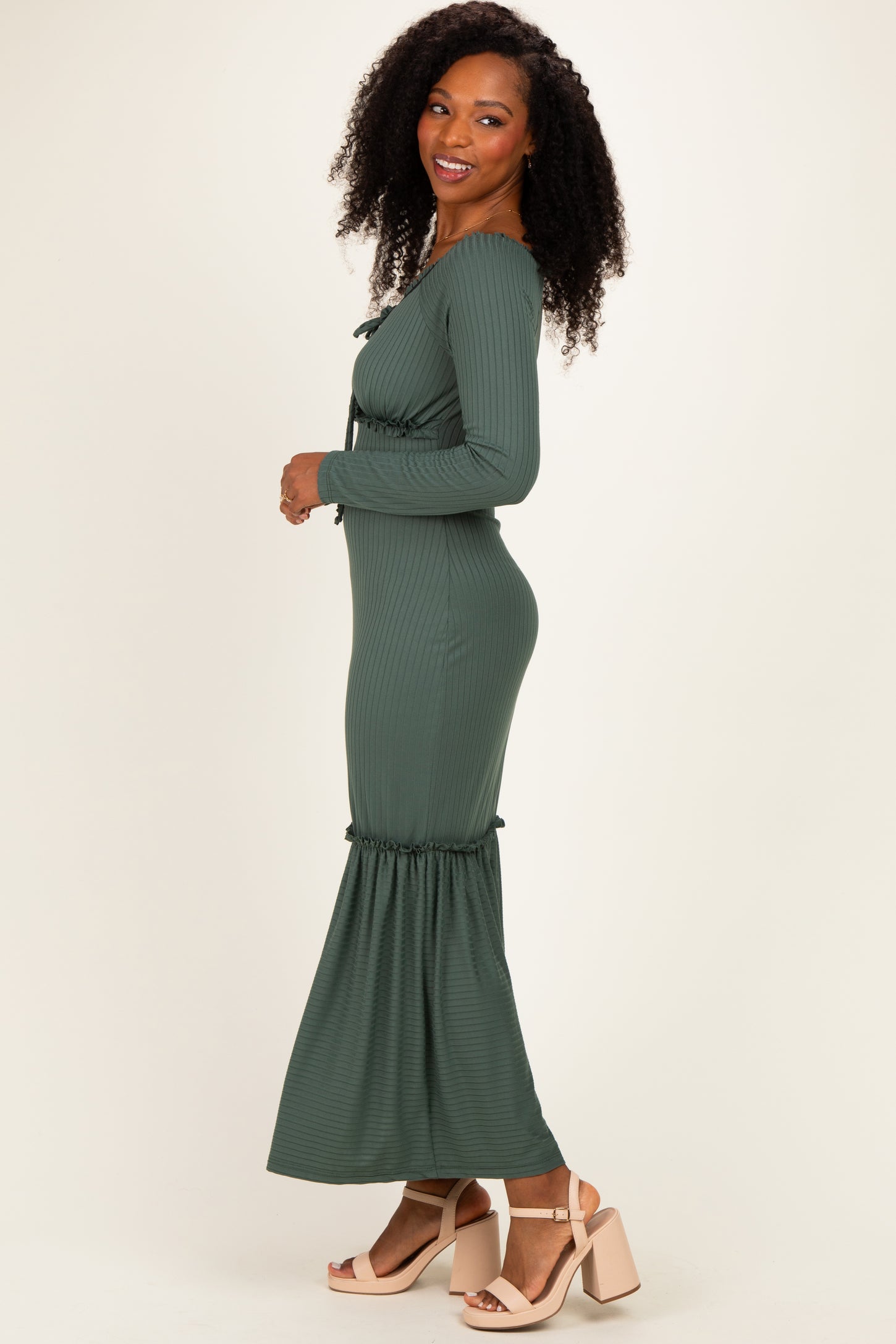 woman wearing a long green ribbed maxi dress with a ruffled hem and a fitted silhouette