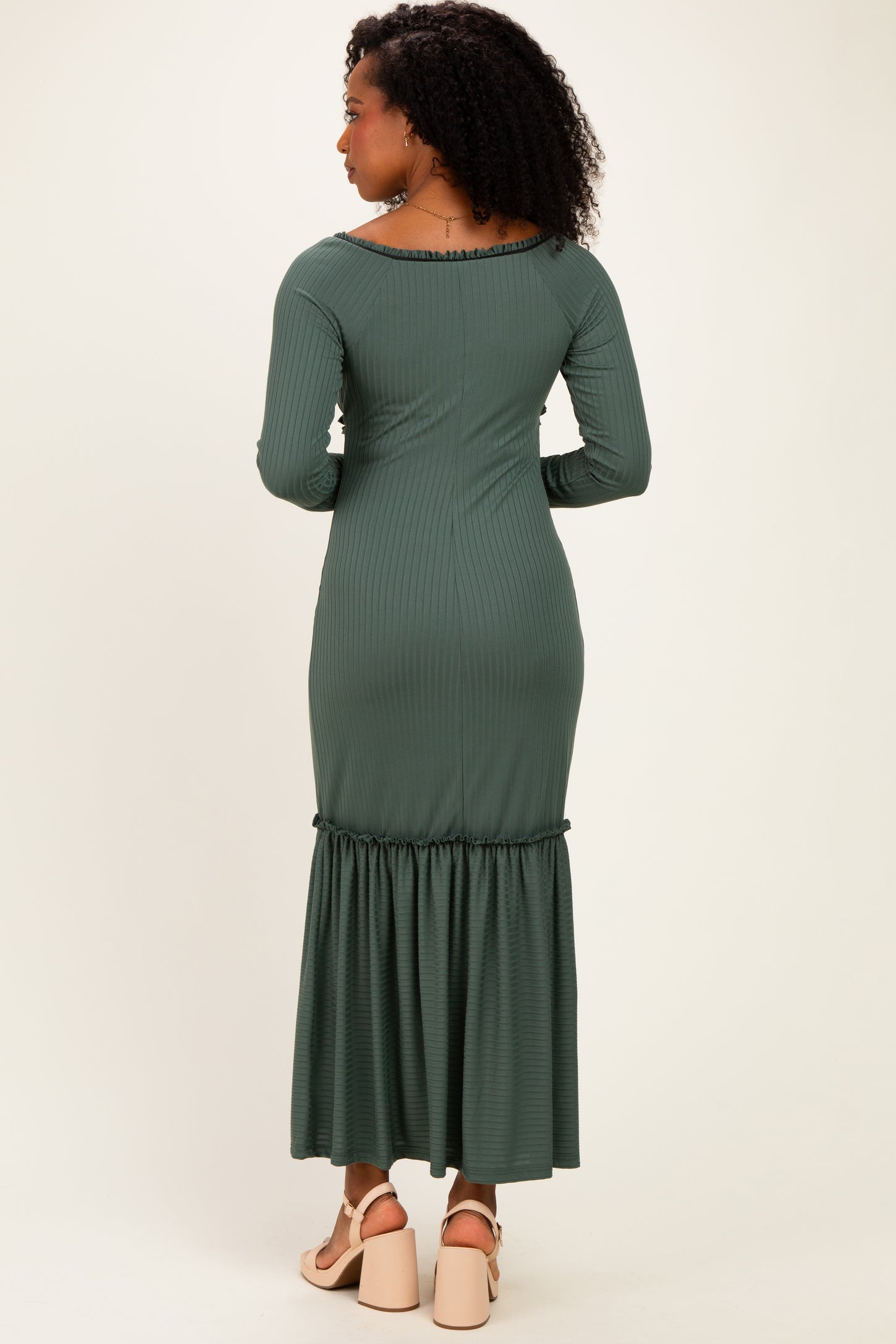 woman wearing a green ribbed long sleeve maxi dress with a ruffled hem, shown from the back