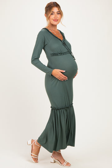 woman wearing a dark green long sleeve maternity dress with a gathered hem and holding her baby bump