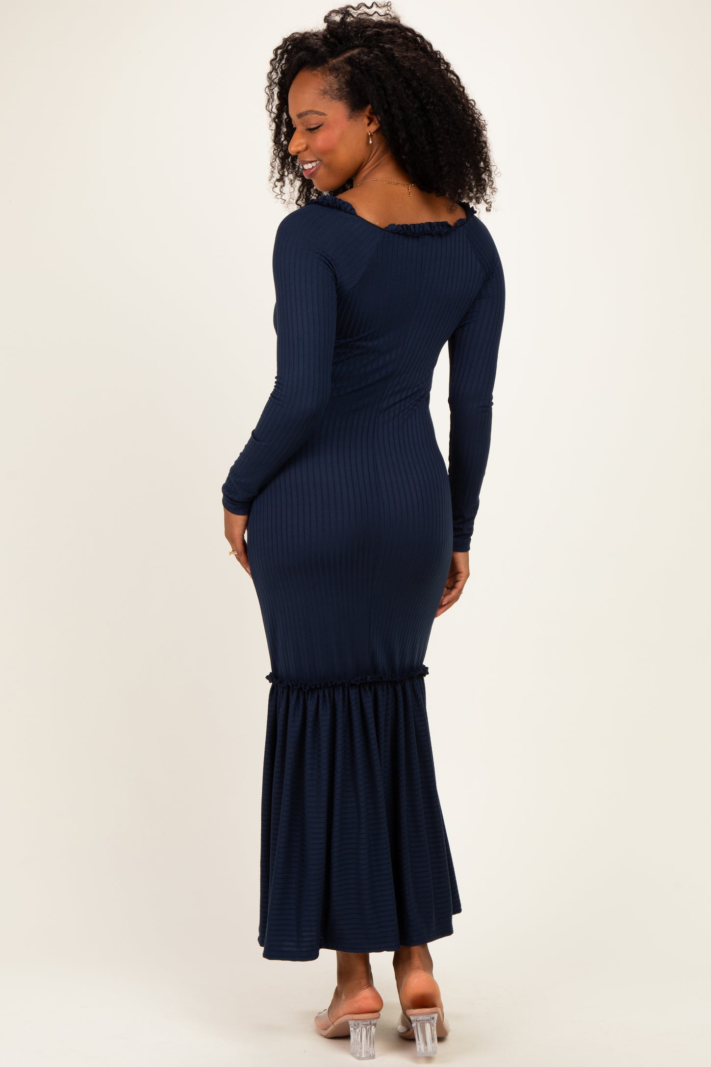 woman wearing a dark blue ribbed maxi dress with long sleeves and a ruffled hem, shown from the back