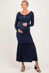 woman wearing a navy blue maternity dress with long sleeves and a ruffled hem, holding her baby bump