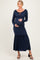 woman wearing a navy blue maternity dress with long sleeves and a ruffled hem, holding her baby bump