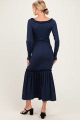woman wearing a navy blue ribbed maternity dress with a ruffled hem and long sleeves, seen from the back