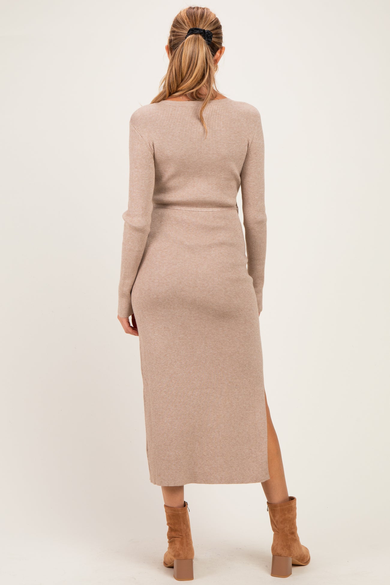 woman wearing a light beige ribbed long sleeve maternity dress with a thigh-high slit, shown from the back