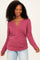 woman wearing a burgundy long sleeve ribbed top with a v-neck and gathered side detail, smiling and posing