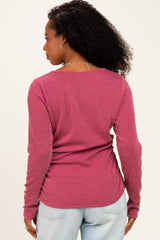 woman wearing a rose pink ribbed long sleeve top, seen from the back with her curly hair cascading down
