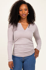 woman wearing a light gray long sleeve ribbed top with a v-neck and styled hair