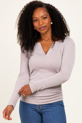woman wearing a light purple ribbed long sleeve top with a v-neck and styled hair, posing with one hand on her arm