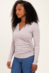 woman wearing a light gray long sleeve ribbed top with a v-neck and ruched sides, styled with blue jeans