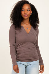 woman wearing a taupe ribbed long sleeve top with a v-neckline and ruched sides, styled with blue jeans