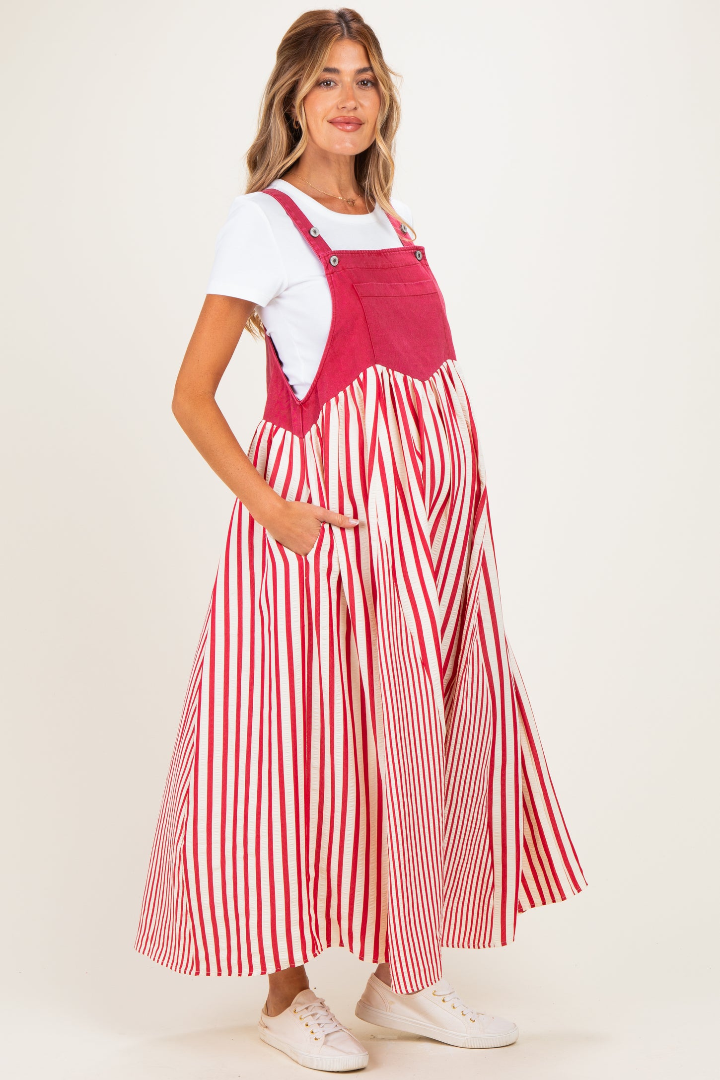 woman wearing a red and white striped maternity dress with pockets over a white top and a visible baby bump