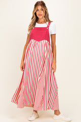 woman wearing a red and white striped maternity maxi dress with adjustable straps over a white t-shirt and white sneakers