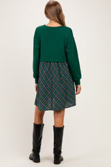 woman wearing a green cropped top with a plaid skirt, styled as maternity wear