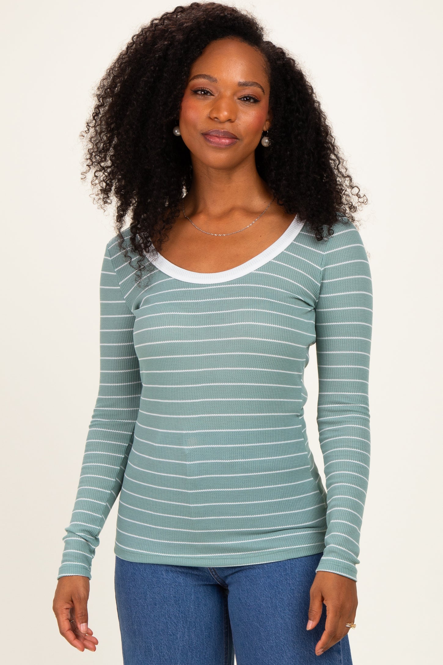 woman wearing a mint green striped long sleeve top with a white scoop neckline