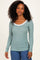 woman wearing a mint green striped long sleeve top with a white scoop neckline
