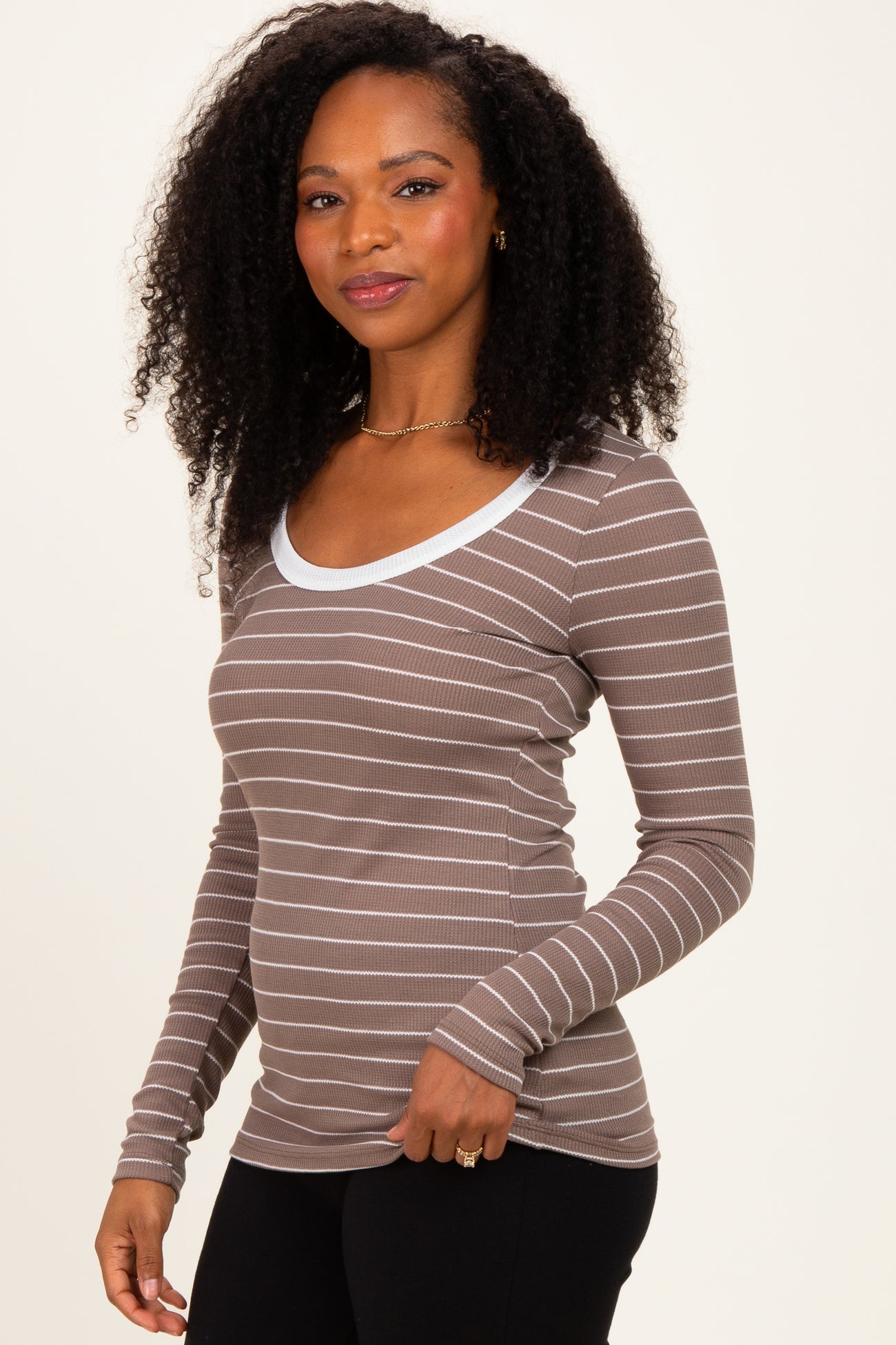 woman wearing a brown and white striped long sleeve top with a scoop neckline and fitted sleeves