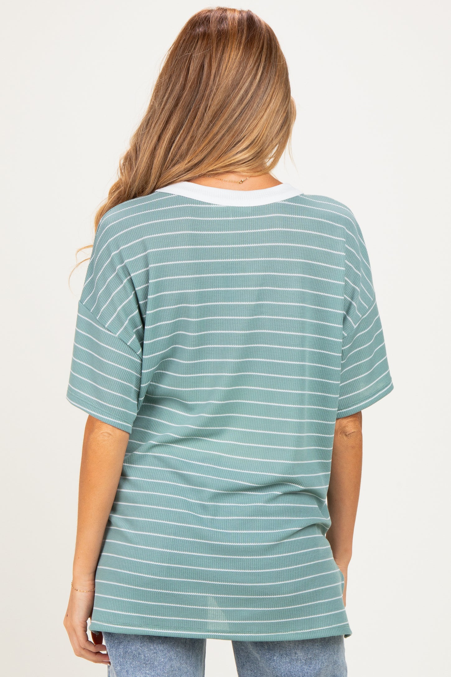 woman wearing a green striped maternity top with a white neckline, shown from the back