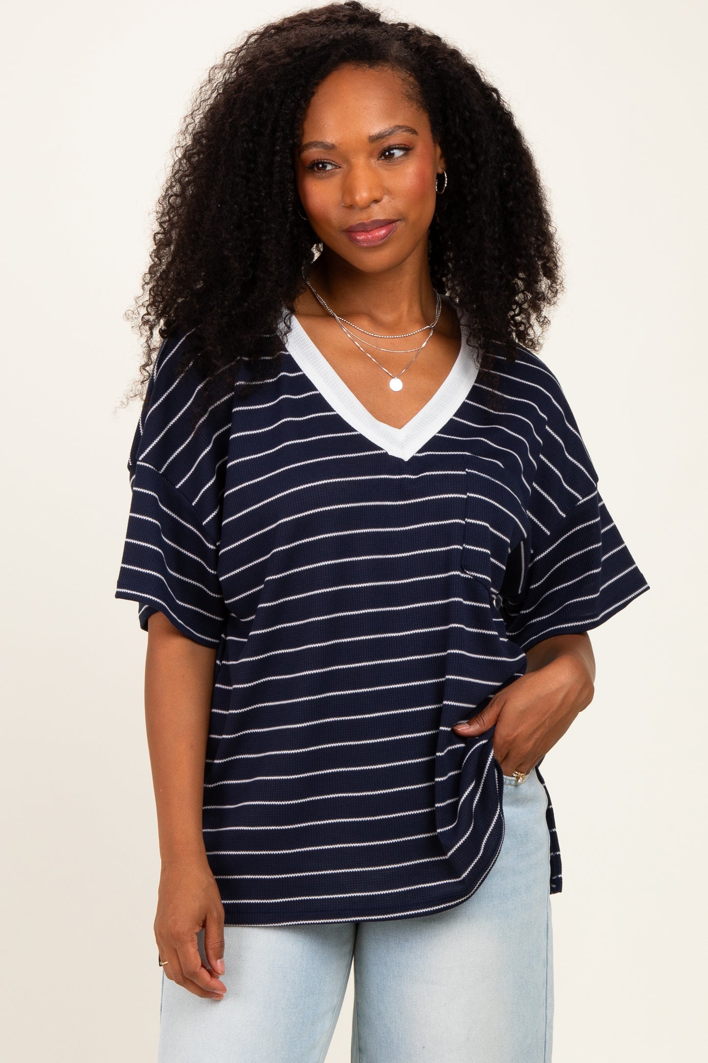 woman wearing a navy blue striped oversized v-neck t-shirt with short sleeves and a pocket detail