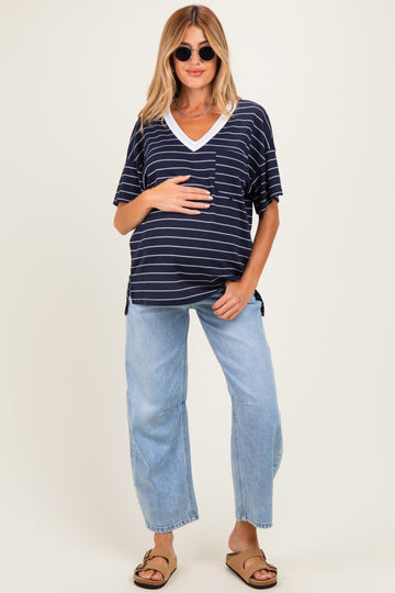 woman wearing a navy and white striped maternity top with a v-neck and holding her baby bump, paired with light blue wide-leg jeans