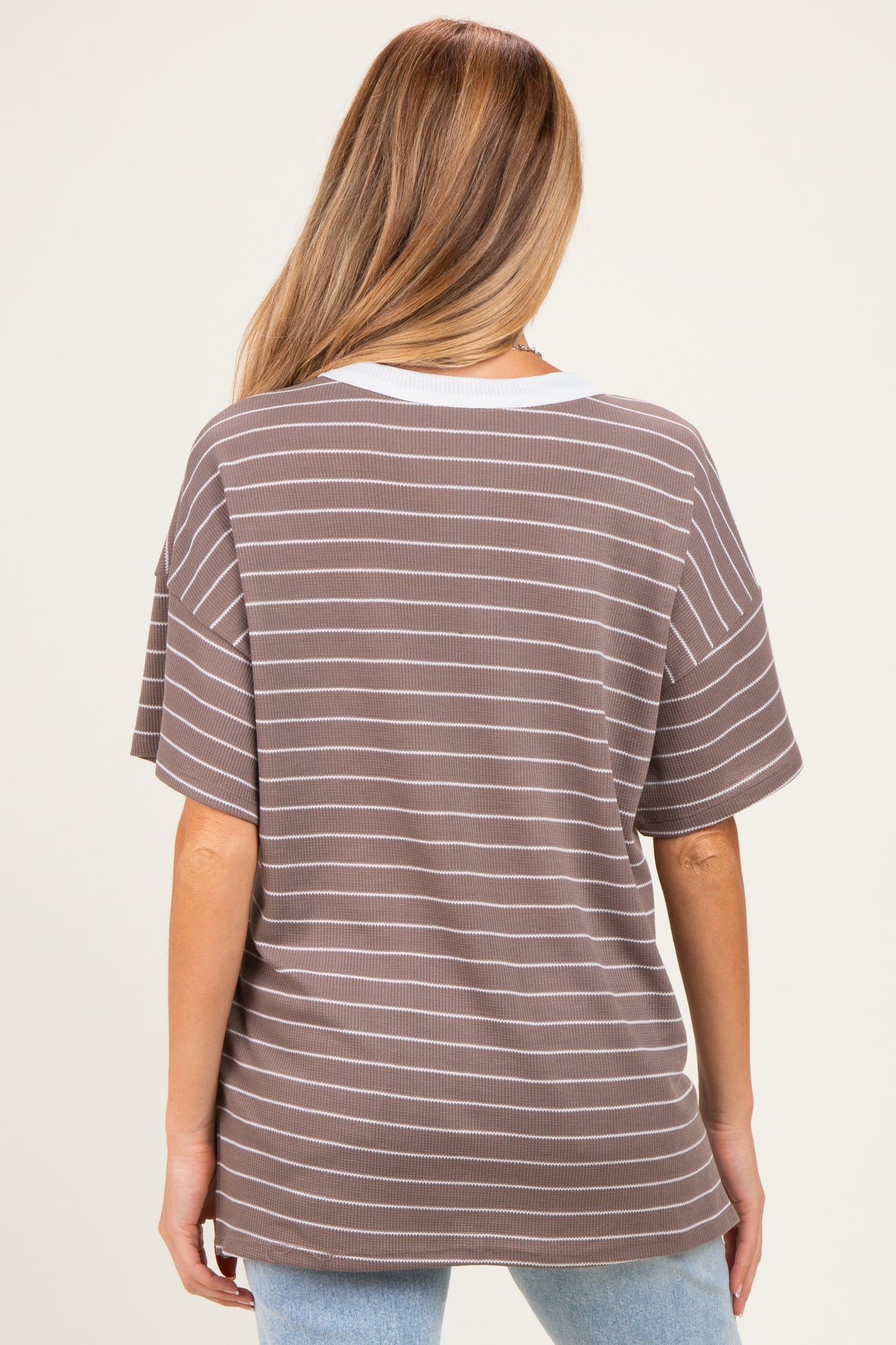 woman wearing a brown and white striped maternity top with a relaxed fit and short sleeves