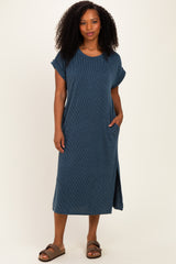 woman wearing a dark blue ribbed short sleeve maxi dress with side pockets and a slit, standing against a neutral background
