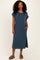 woman wearing a dark blue ribbed short sleeve maxi dress with side pockets and a slit, standing against a neutral background