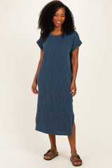 woman wearing a dark blue ribbed midi dress with short sleeves and side slits, standing and smiling