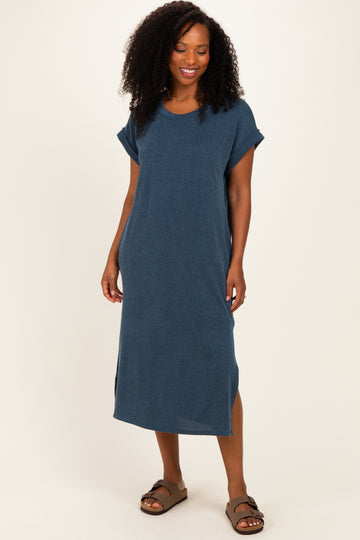 woman wearing a dark blue ribbed midi dress with short sleeves and side slits, standing and smiling