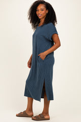 woman wearing a dark blue ribbed midi dress with short sleeves and pockets, styled with brown slide sandals