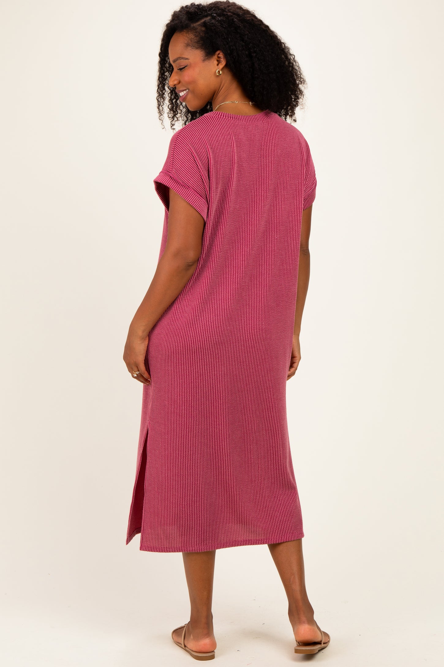 woman wearing a maroon ribbed midi dress with short sleeves and side slits, seen from the back