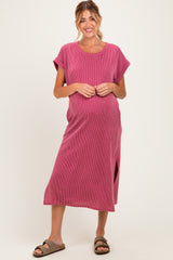 woman wearing a pink striped maternity maxi dress with short sleeves and a side slit, gently cradling her baby bump