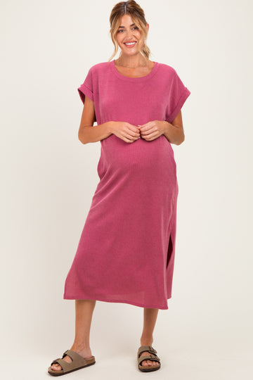 woman wearing a pink striped maternity maxi dress with short sleeves and a side slit, gently cradling her baby bump