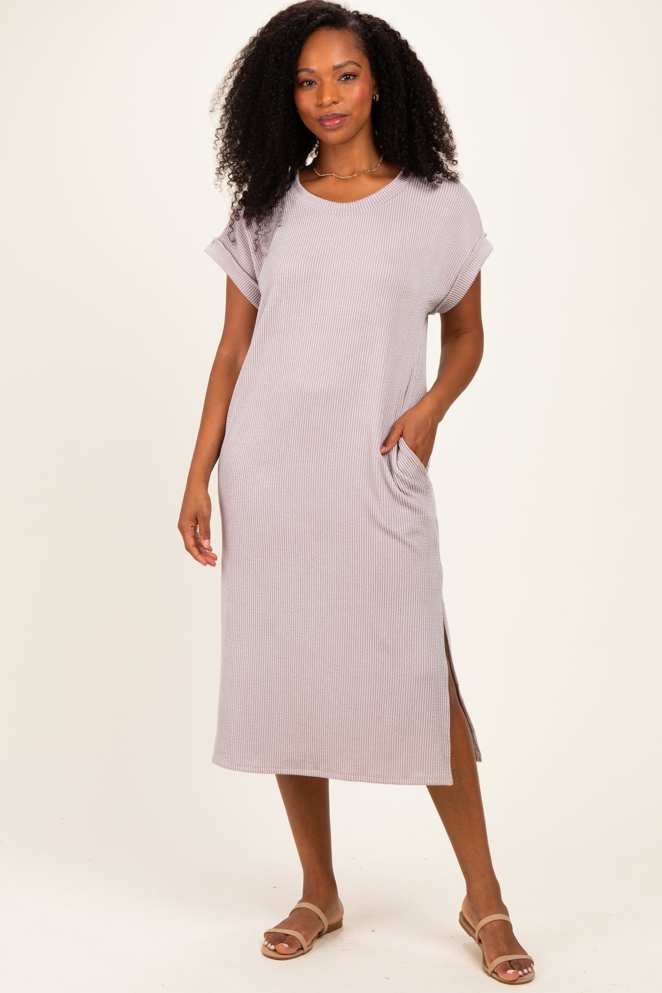 woman wearing a light mauve ribbed short sleeve midi dress with side slits and pockets
