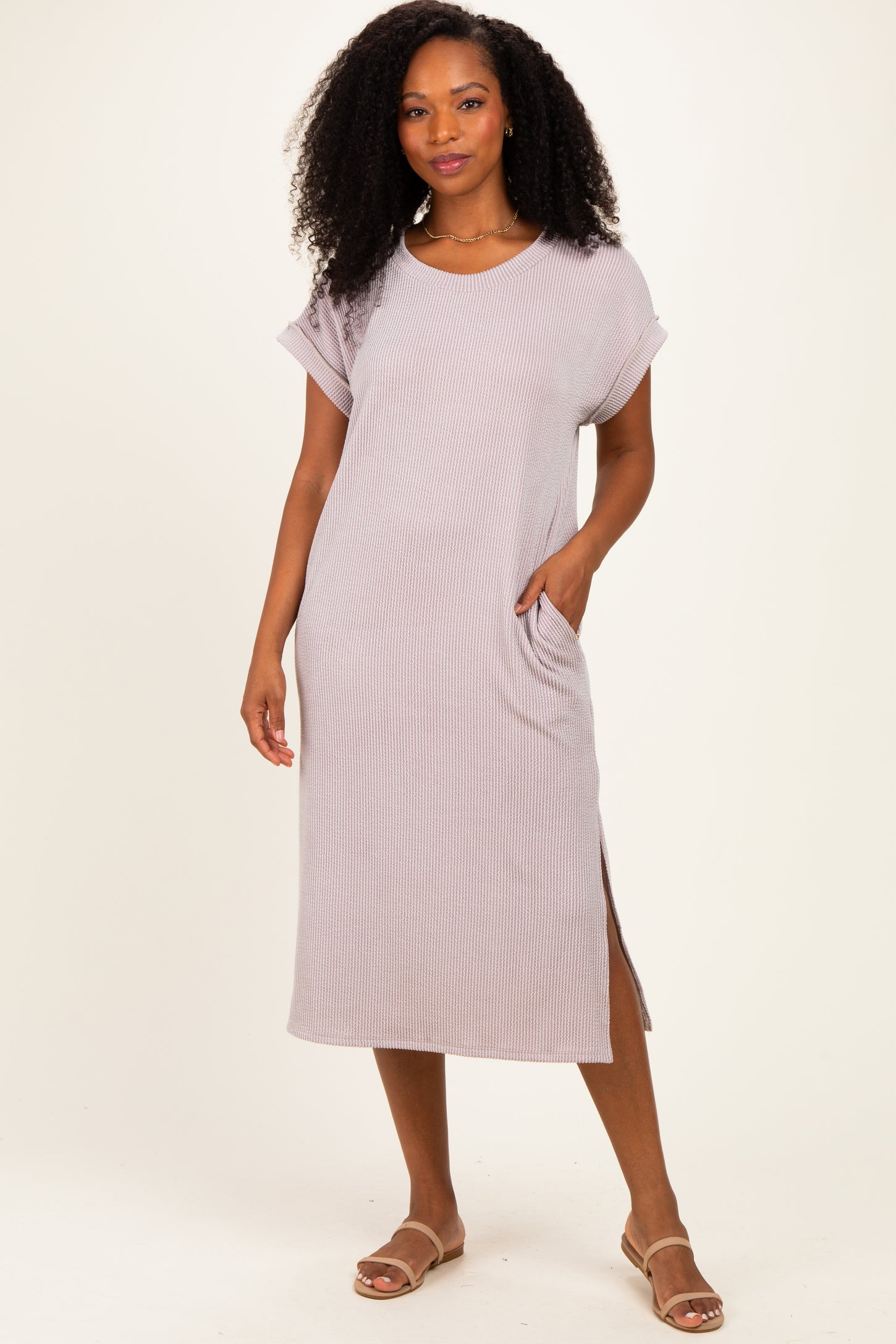 woman wearing a light mauve ribbed short sleeve midi dress with side slits and pockets